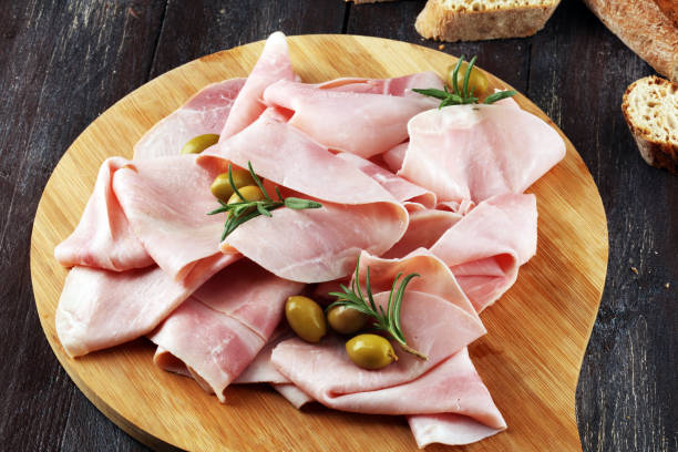 istock Sliced ham on wooden background. Fresh prosciutto. Pork ham sliced. 1070236252