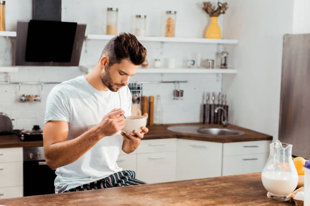 istock young man in pajamas eating corn flakes for breakfast at home 1070242900