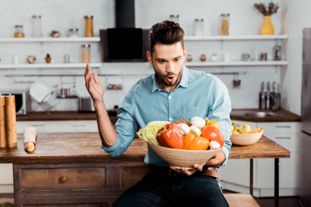 istock excited young man holding bowl with fresh vegetables in kitchen 1070243100
