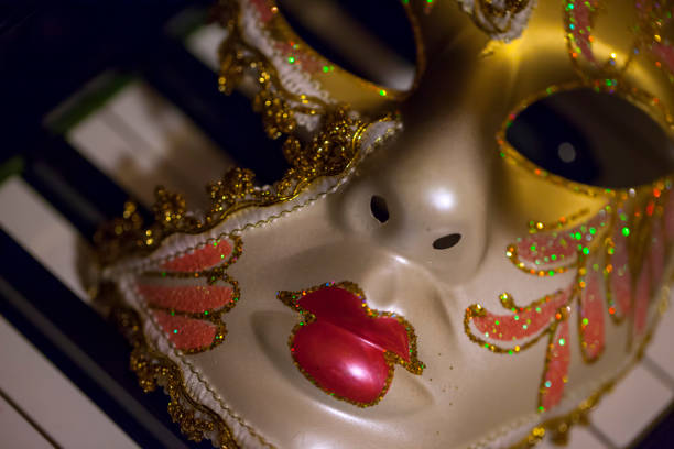 Carnival venetian mask with golden stars confetti on deep red background close up. Luxury masquerade mask. Purim party template.