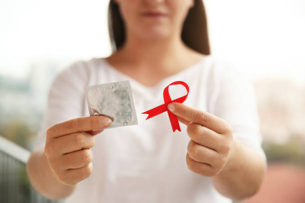 Woman with aids ribbon and condom stock photo