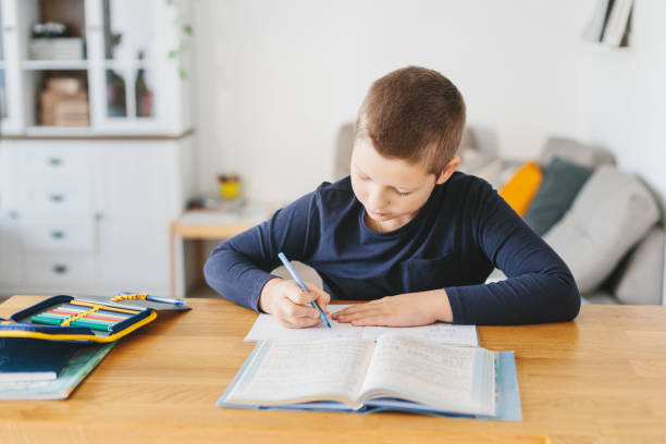 istock Schoolboy doing his homework on desk at home. 1070259432