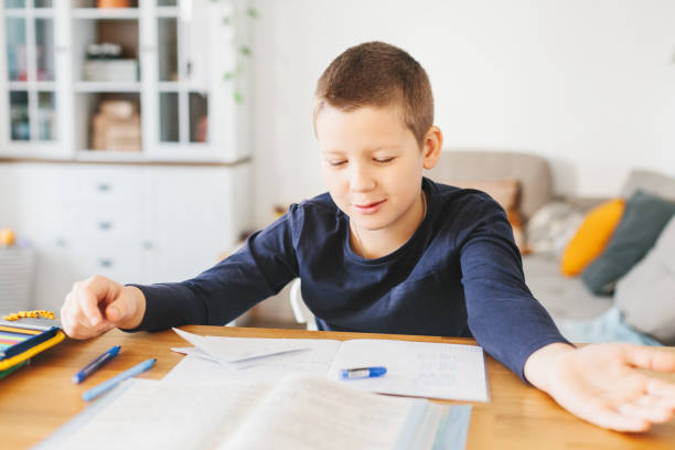 istock Schoolboy doing his homework on desk at home. 1070259512