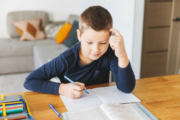 istock Schoolboy doing his homework on desk at home. 1070260626