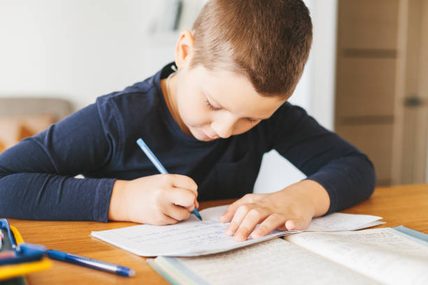 istock Schoolboy doing his homework on desk at home. 1070260646