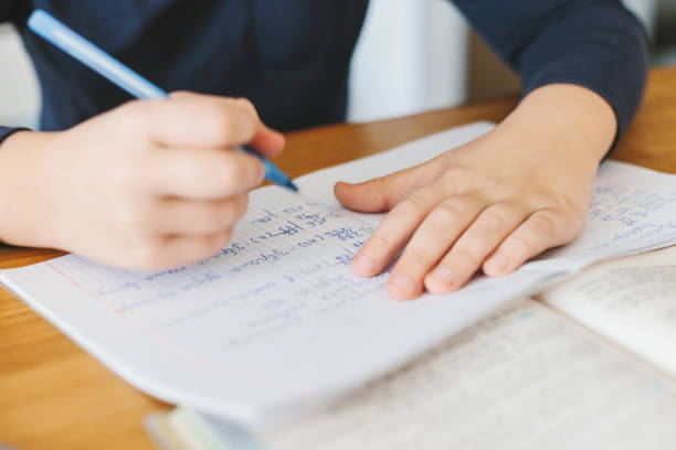 Schoolboy doing his homework on desk at home.