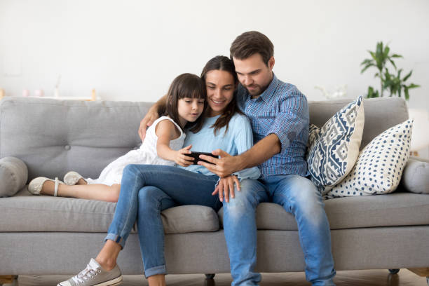 istock Family sitting on sofa using smartphone watching video 1070261806