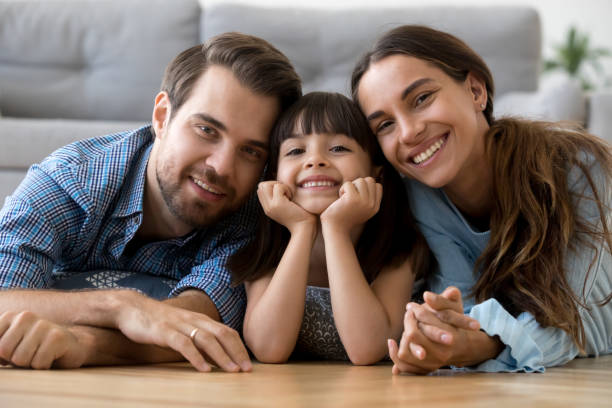 istock Happy diverse family lying on warm floor looking at camera 1070261900