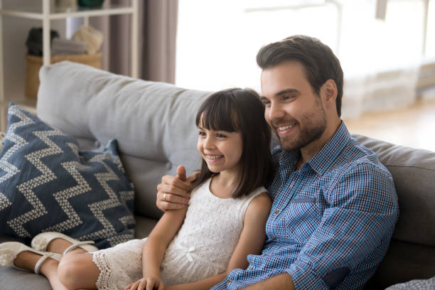 istock Father embrace daughter sitting together on couch 1070262112