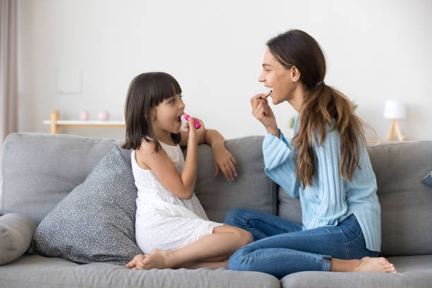 istock Little daughter having fun with mommy applying lipstick on lips 1070262176
