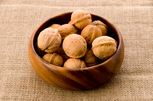 istock Walnuts in the wooden bowl, on burlap background. 1070262994