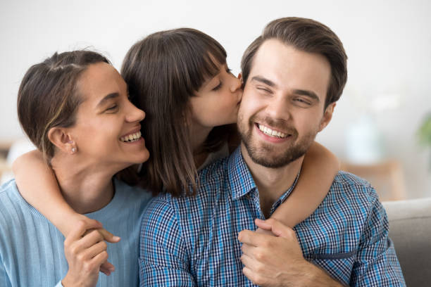 istock Daughter kissing father sitting together on sofa 1070267274