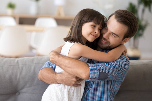 istock Little daughter looking at father with love embracing him 1070267334