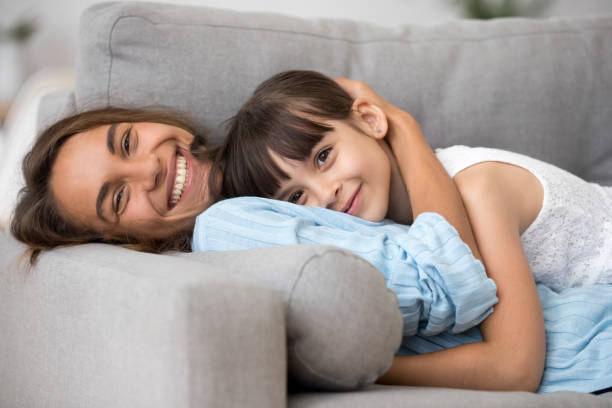 istock Happy mother and adorable daughter lying on sofa 1070267420