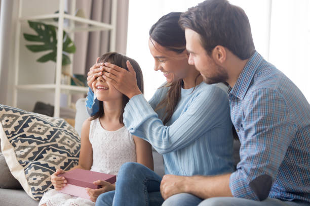 istock Diverse parents sitting on couch prepare for daughter gift 1070267428