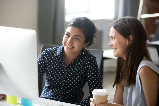 istock Smiling diverse female interns talking in office discussing online work 1070271482