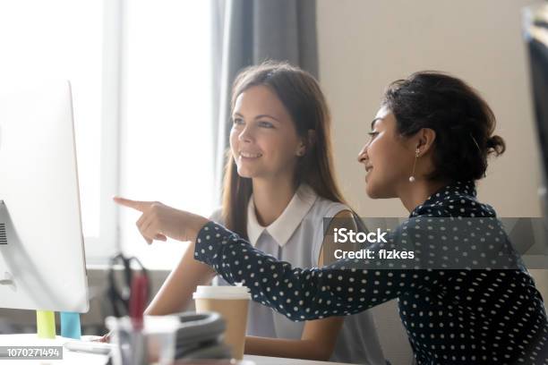 Happy Caucasian Intern Listening To Indian Mentor Explaining Computer Task Stock Photo - Download Image Now