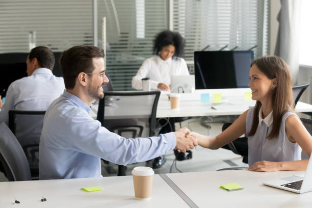 istock Smiling male and female colleagues handshaking thanking for successful work 1070271506