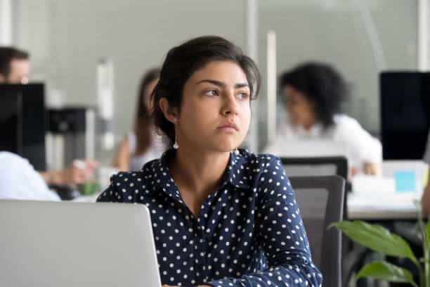 Thoughtful indian businesswoman looking away thinking of problem solution Thoughtful indian business woman looking away feeling bored pensive thinking of problem solution in office with laptop, serious hindu employee searching new ideas at work unmotivated about dull job laziness photos stock pictures, royalty-free photos & images
