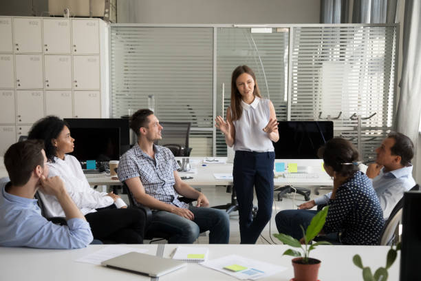istock Friendly young female worker speaking at diverse corporate group meeting 1070271748