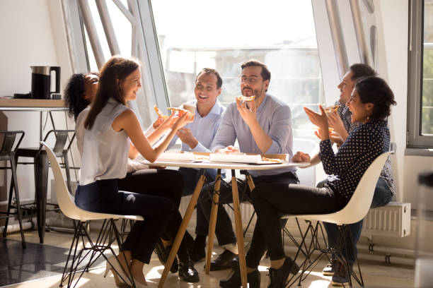 istock Friendly happy diverse workers laughing eating pizza together in office 1070271788