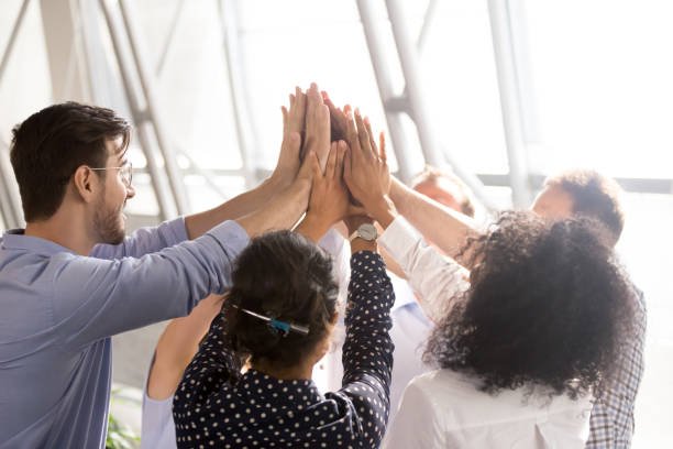 Diverse business team office workers group giving high five together Diverse business team associates office workers group giving high five together as concept of coaching, teamwork involvement, engaging in teambuilding, motivated by unity, good corporate relations sales win stock pictures, royalty-free photos & images