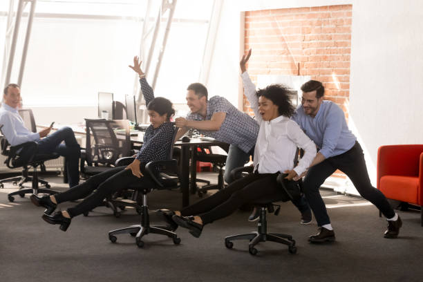 istock Carefree excited diverse office workers having fun riding oh chairs 1070271796