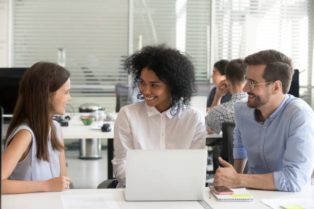 uśmiechnięci wielorasowi mentorzy szkolący stażystę z komputerem w biurze - team concentration assistance support zdjęcia i obrazy z banku zdjęć