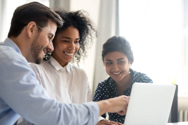 Diverse happy interns listening to mentor explaining online project