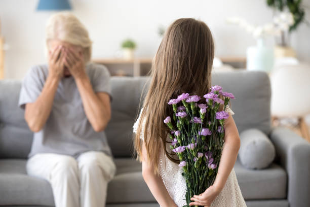 kleines mädchen macht überraschung für großmutter halten blumen - besondere anlässe stock-fotos und bilder