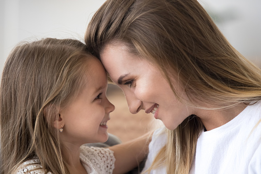 Loving mom and daughter embrace looking in eyes enjoying tender moment together, cute caring mother and child hug touching foreheads, having close strong connection. Bonding, family concept