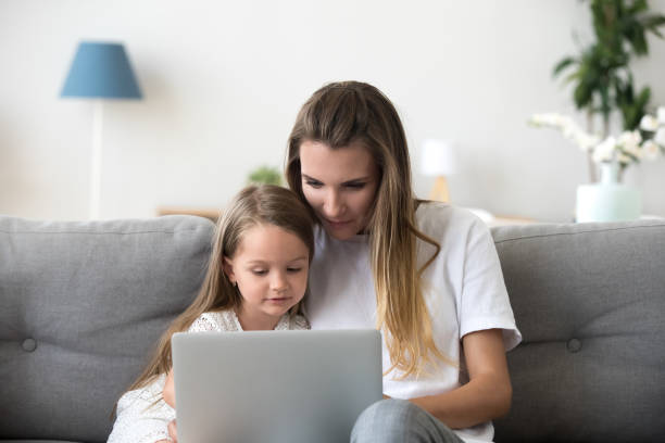 istock Mother and daughter relax on couch using laptop 1070272138