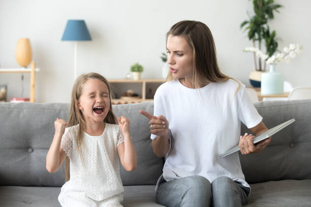 Strict mom scolding ill-behaved daughter screaming loud at home Stubborn little girl scream loud not listening to strict mom, serious young mother scold shouting daughter for bad behavior, working mommy lecture kid yelling asking attention. Family conflict concept  positive discipline in kids stock pictures, royalty-free photos & images