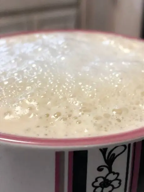 A close-up of a frothy cup of coffee with (almond) milk.