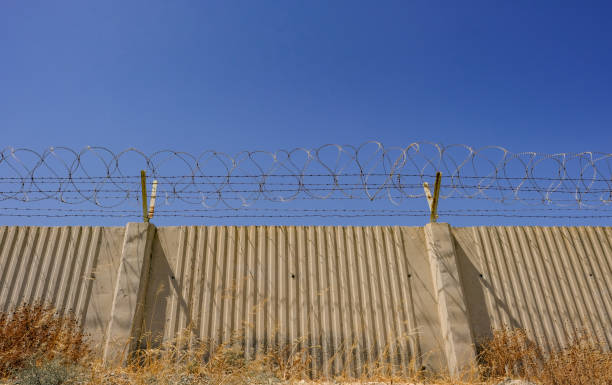 istock Concrete wall with barbed wire on top. 1070276102