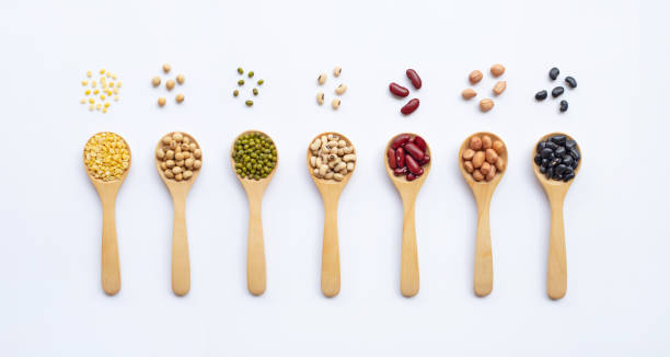 istock Different types of legumes on wooden spoon, white background. 1070279042