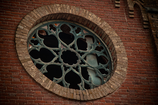 Round castle window with broken stained-glass windows.