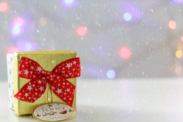 istock Gift box with red bow and defocused christmas lights on the background. With snow effect 1070319308