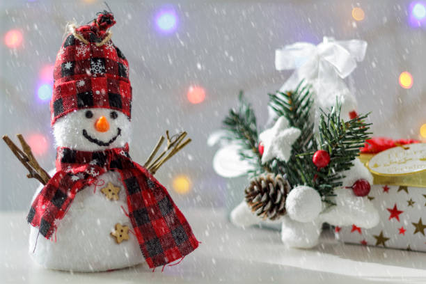 istock Snowman with christmas tree, gift boxes and christmas lights on the background. With snow effect 1070319330