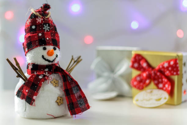 istock Snowman with gift boxes and christmas lights on the background 1070319670