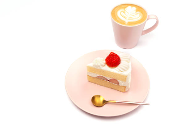 Japanese style strawberry shortcake on the pink plate and cup of coffee with latte art. White background. Side view, copy space for your text.