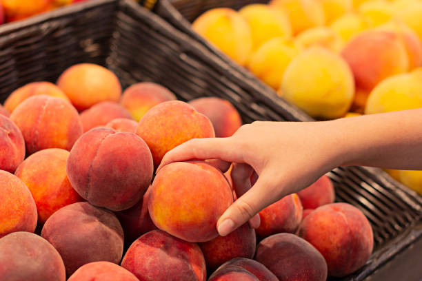 Female hand choosing peaches in the market