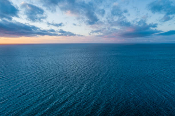 istock Tranquil seascape - clouds over calm water and tiny lonely boat at dusk 1070326472