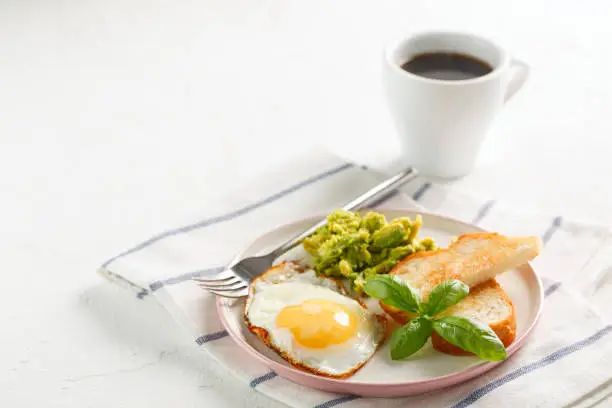 Photo of healthy breakfast. egg, avocado, toasts and basil