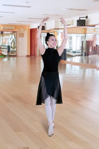 Portrait of Asian woman looks happy while dancing with graceful pose in a ballet class