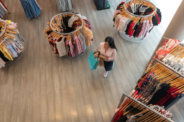 donna latinoamericana che cammina in un negozio di abbigliamento mentre tiene le borse della spesa - department store foto e immagini stock