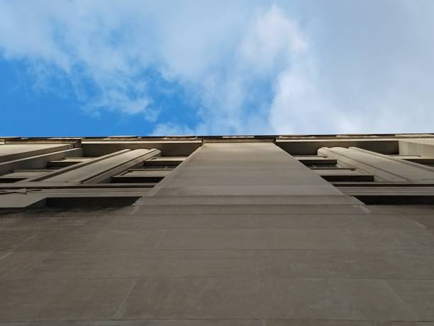 Exterior of historic stone building in New York City. Shot from low angle looking at roof to diminishing viewpoint against blue sky.
