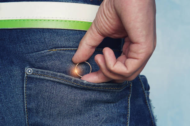 cerca de un joven en mano o sacar un anillo de bodas en el bolsillo de los pantalones vaqueros. concepto de infidelidad o pidiendo en matrimonio. hombre saca anillo antes de la infidelidad. hombre hace una propuesta de matrimonio - women bride personal accessory adult fotografías e imágenes de stock