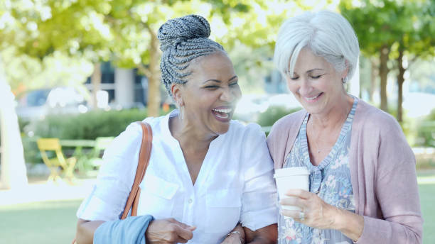 istock Two senior women walk through a park together and smile 1070362474