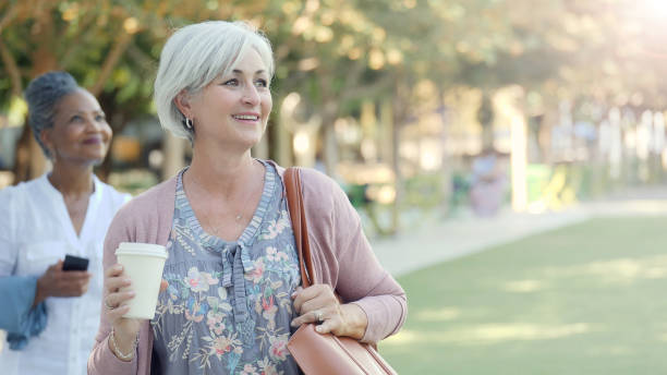 istock Two smiling senior women walk around a park 1070362500